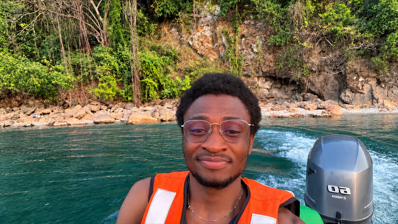 Francis on a boat wearing an orange life jacket