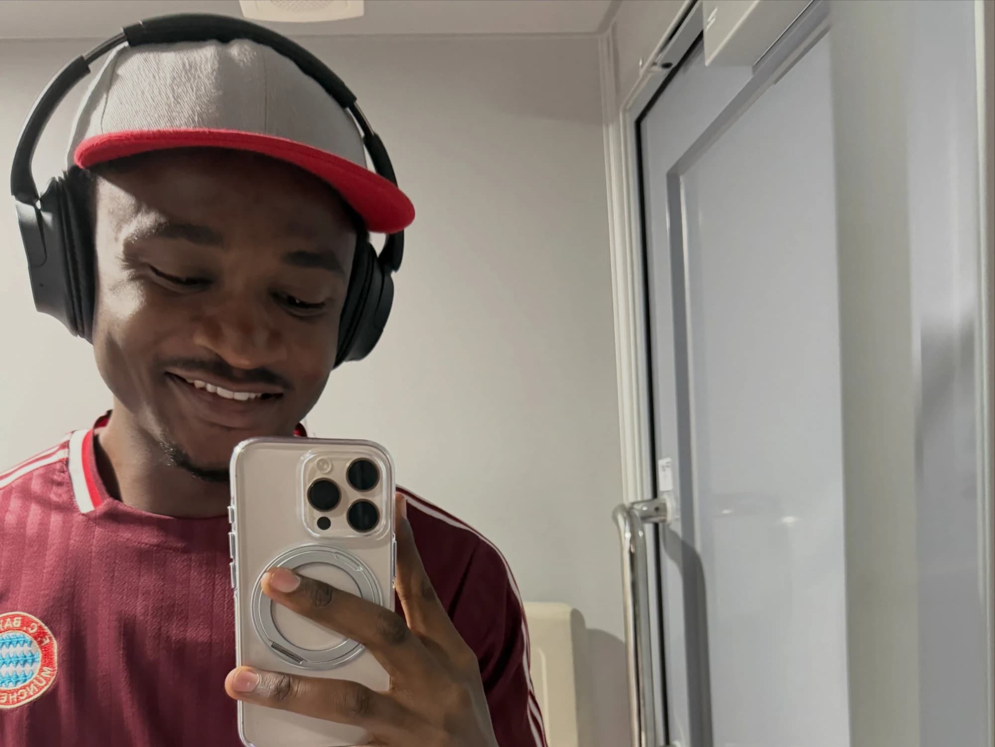 Francis smiling in a mirror with headphones and a red cap